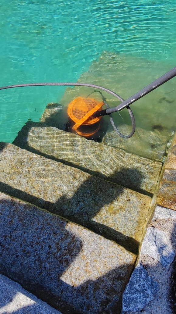 Naturpoolreinigung. Motorbürste bei der Treppenreinigung